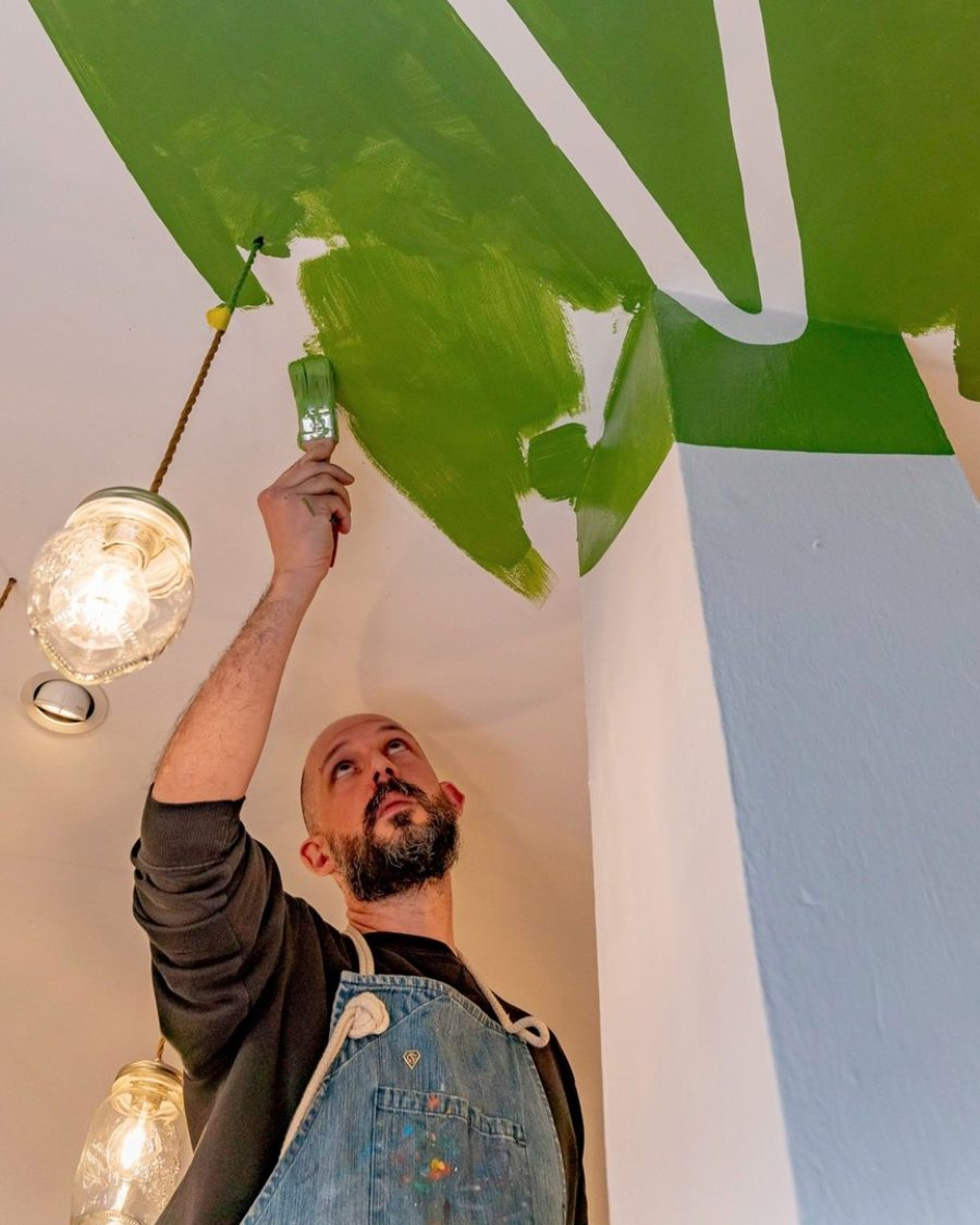 Simone Cannolicchio dipinge a pennello il logo anamorfico sul soffitto della gelateria